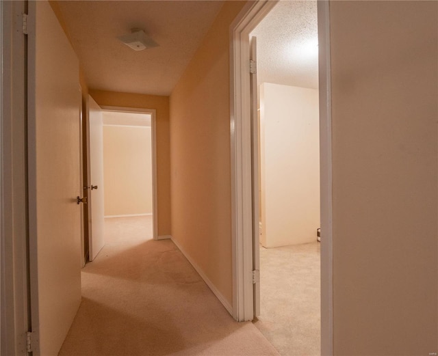 hallway featuring a textured ceiling and light colored carpet