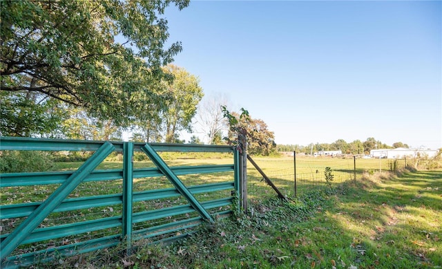 view of gate with a lawn and a rural view