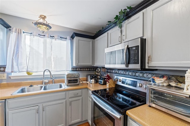 kitchen featuring gray cabinetry, tasteful backsplash, appliances with stainless steel finishes, sink, and pendant lighting