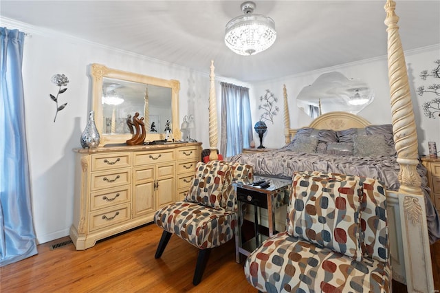 bedroom with ornamental molding, light hardwood / wood-style flooring, and an inviting chandelier