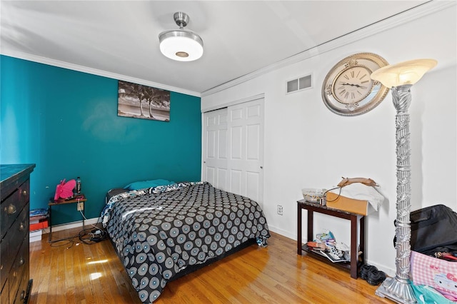 bedroom with crown molding, hardwood / wood-style flooring, and a closet