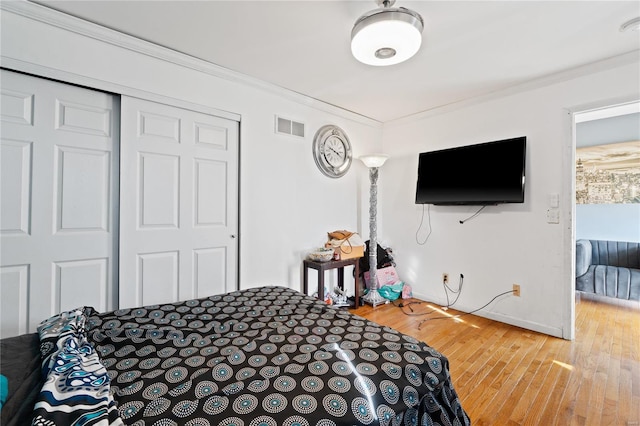 bedroom featuring a closet, crown molding, and hardwood / wood-style floors