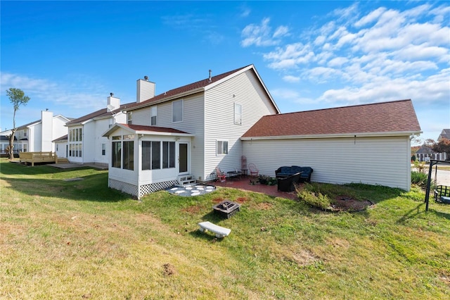 rear view of house featuring a sunroom and a lawn