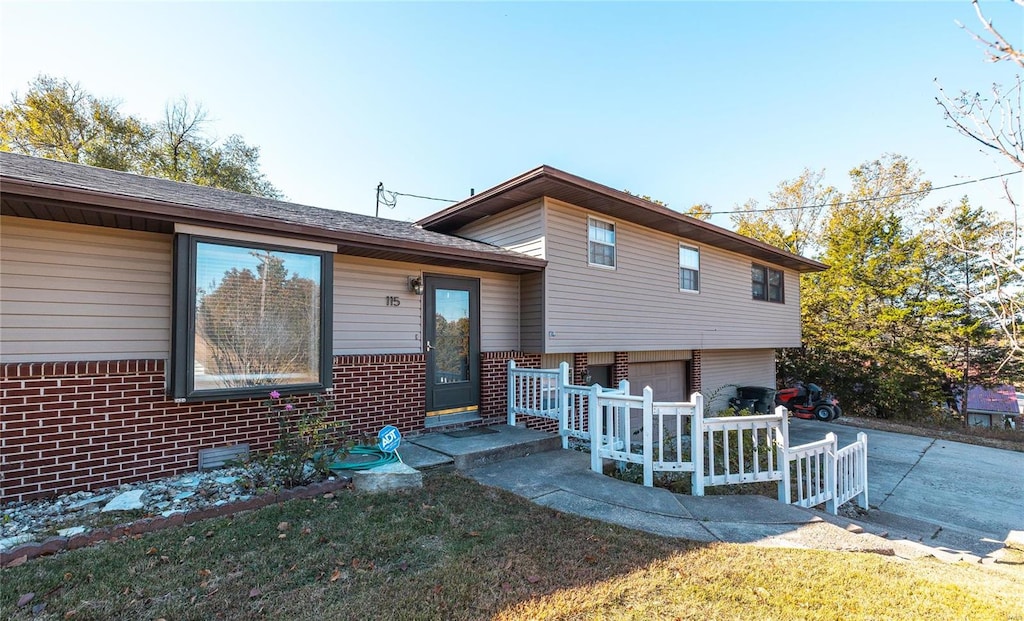 tri-level home featuring a garage and a front lawn