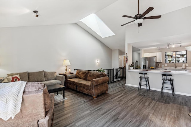 living room featuring a skylight, dark hardwood / wood-style floors, high vaulted ceiling, and ceiling fan