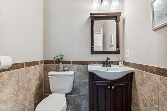 bathroom featuring vanity, toilet, and tile walls