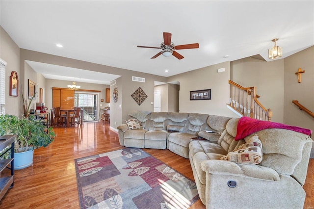 living room with light hardwood / wood-style floors and ceiling fan with notable chandelier