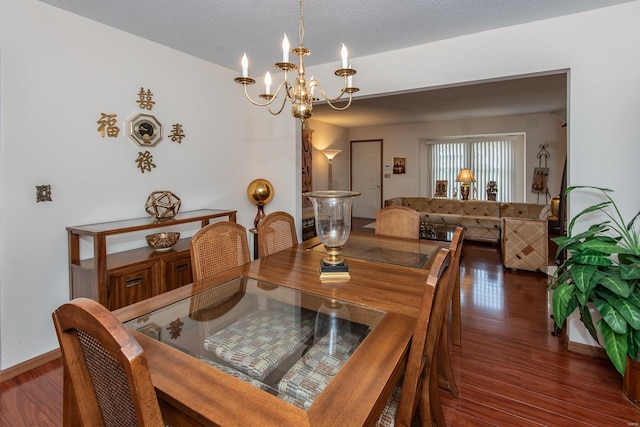 dining room with a textured ceiling, dark hardwood / wood-style flooring, and an inviting chandelier