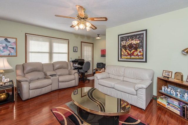 living room featuring dark wood-type flooring, a textured ceiling, and ceiling fan