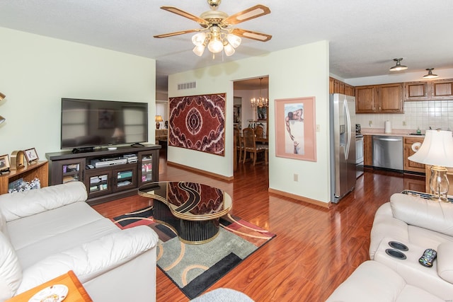 living room featuring dark wood-type flooring, a textured ceiling, and ceiling fan with notable chandelier