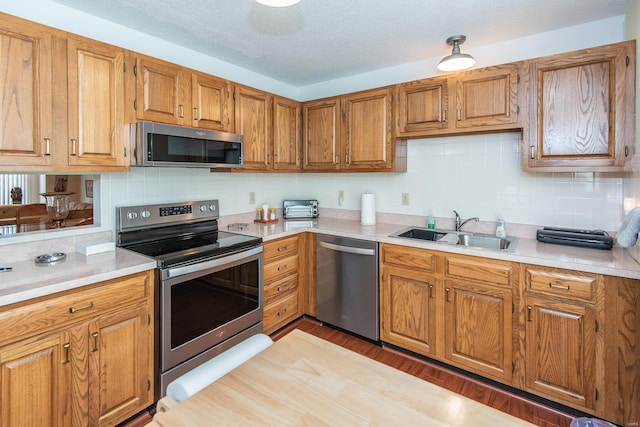 kitchen featuring decorative backsplash, a textured ceiling, dark hardwood / wood-style floors, sink, and stainless steel appliances