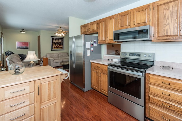 kitchen featuring dark wood-type flooring, ceiling fan, stainless steel appliances, and tasteful backsplash