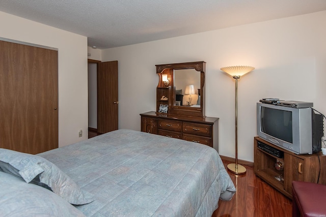 bedroom featuring dark wood-type flooring, a closet, and a textured ceiling