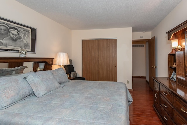 bedroom featuring a textured ceiling, a closet, and dark hardwood / wood-style flooring