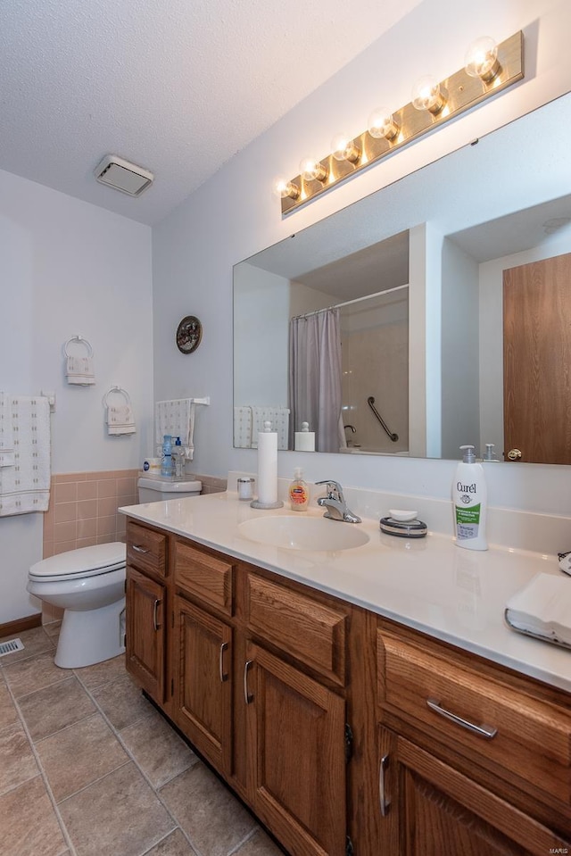 bathroom with toilet, tile patterned flooring, vanity, a textured ceiling, and walk in shower