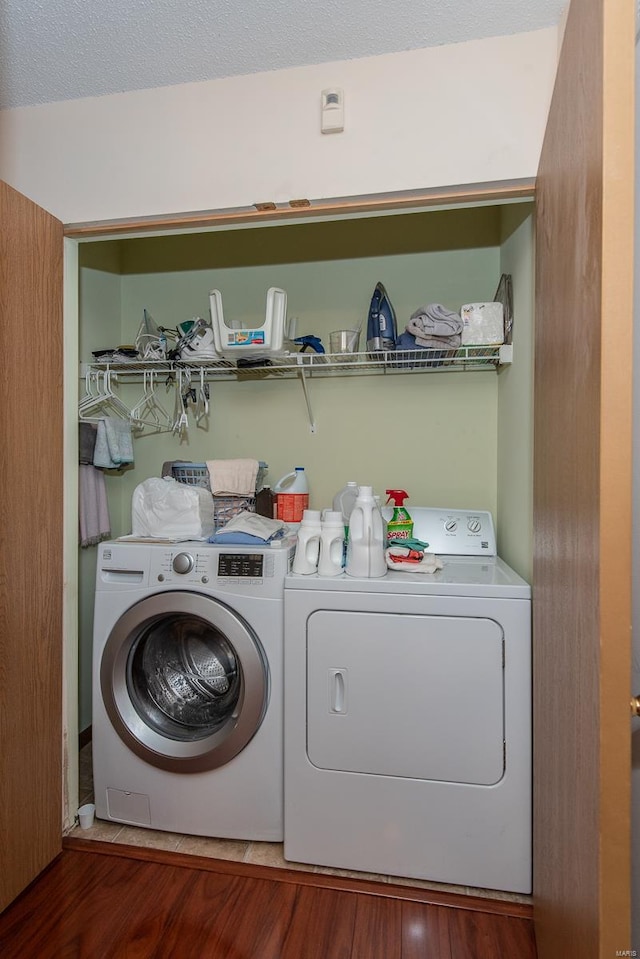 laundry area with a textured ceiling, wood-type flooring, and washer and clothes dryer