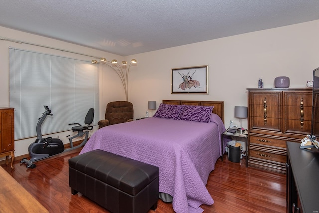 bedroom with a textured ceiling and dark hardwood / wood-style flooring