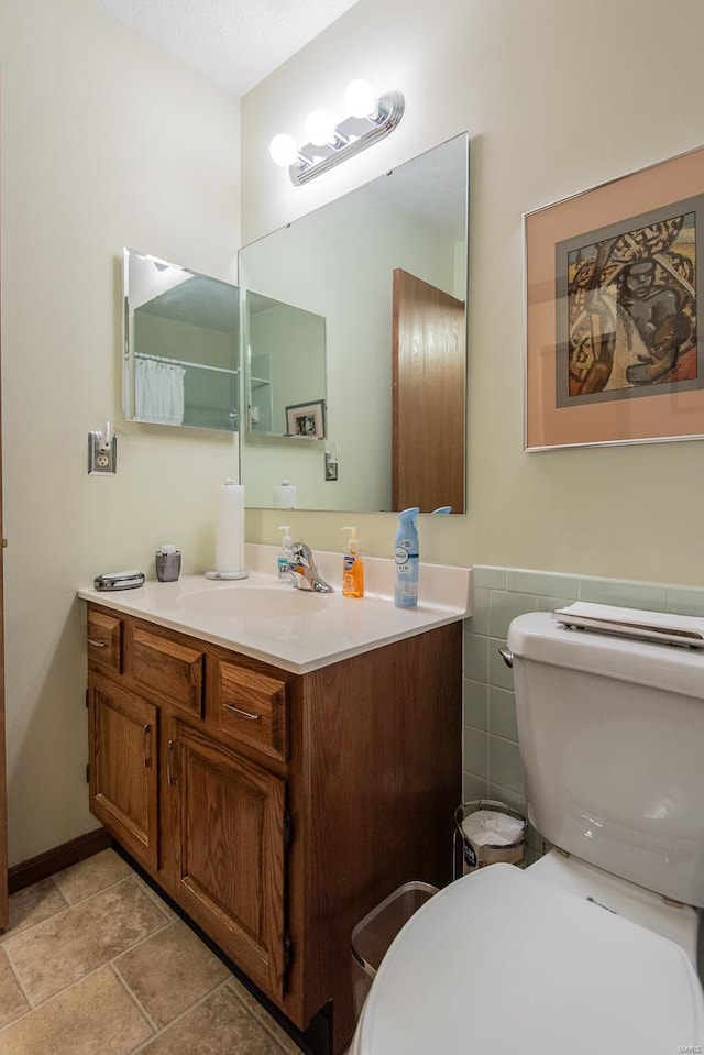 bathroom with tile walls, vanity, and toilet