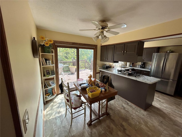 kitchen featuring kitchen peninsula, dark brown cabinets, ceiling fan, a textured ceiling, and stainless steel refrigerator