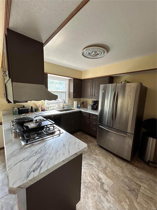 kitchen with cooktop, sink, a textured ceiling, dark brown cabinetry, and stainless steel refrigerator