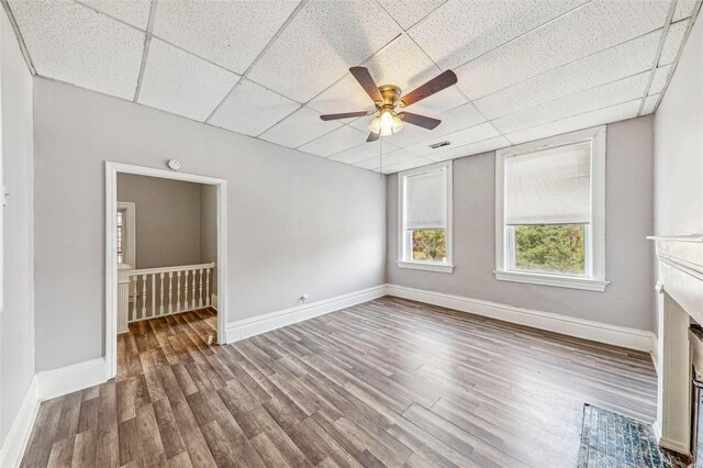 unfurnished living room featuring a drop ceiling, hardwood / wood-style flooring, and ceiling fan