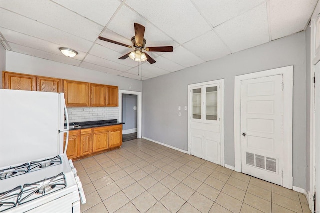 kitchen with decorative backsplash, a drop ceiling, white appliances, and light tile patterned floors