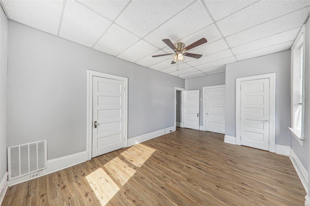 unfurnished bedroom with ceiling fan, a drop ceiling, and hardwood / wood-style floors