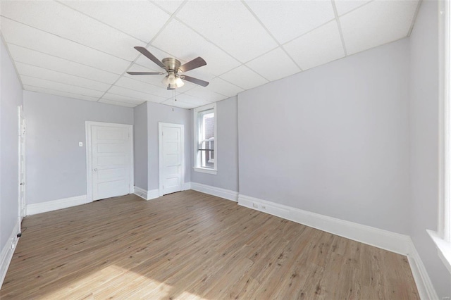 unfurnished room with a drop ceiling, hardwood / wood-style flooring, and ceiling fan