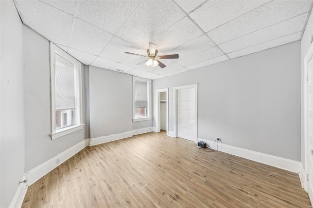 unfurnished room with a drop ceiling, light wood-type flooring, and ceiling fan