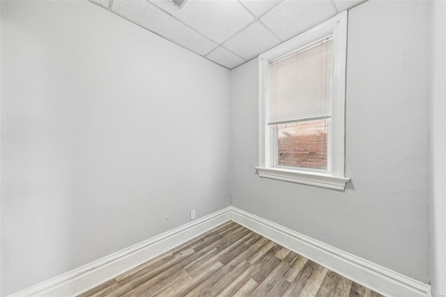 spare room with a drop ceiling and wood-type flooring