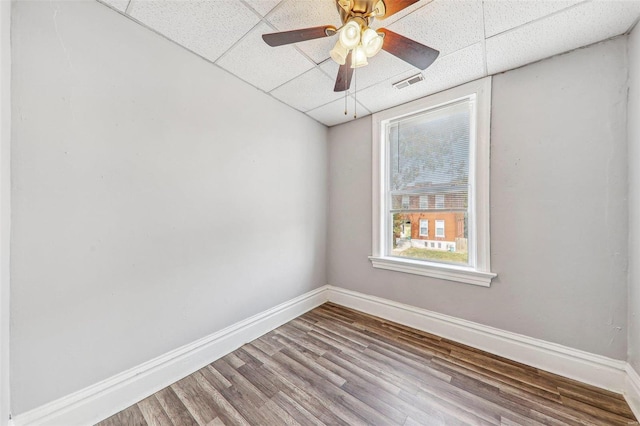 empty room featuring a paneled ceiling, wood-type flooring, and ceiling fan