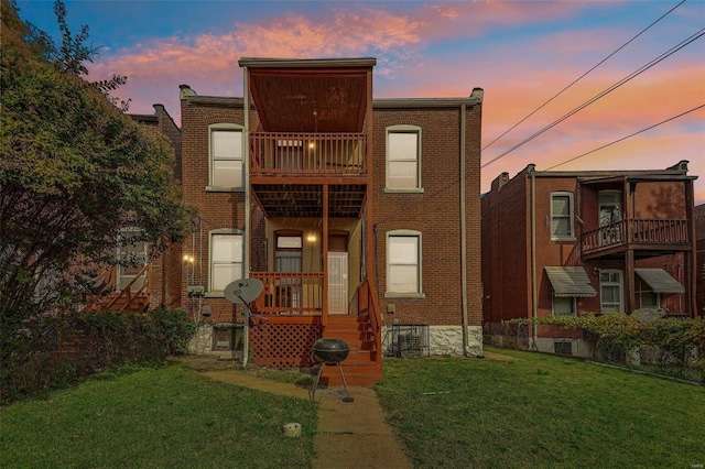 back house at dusk with a lawn and a balcony