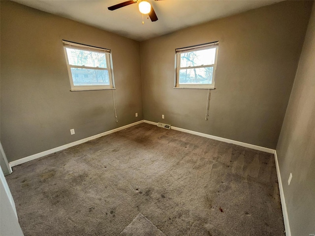 spare room featuring dark colored carpet, plenty of natural light, and ceiling fan