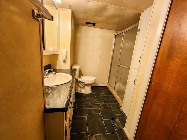 bathroom with vanity, toilet, and a shower with door