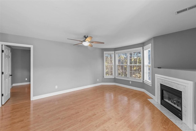 unfurnished living room with light hardwood / wood-style flooring, a high end fireplace, and ceiling fan