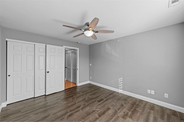 unfurnished bedroom with dark wood-type flooring, two closets, and ceiling fan