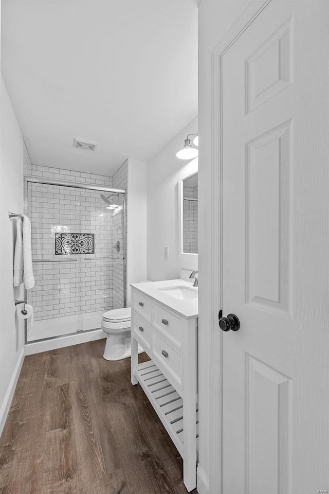 bathroom featuring vanity, hardwood / wood-style flooring, toilet, and walk in shower