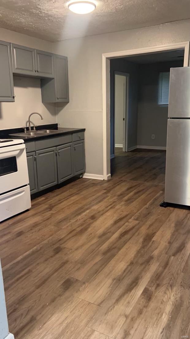 kitchen with white range oven, gray cabinetry, stainless steel fridge, and dark hardwood / wood-style flooring