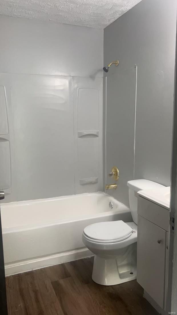 full bathroom with hardwood / wood-style floors, vanity, washtub / shower combination, toilet, and a textured ceiling