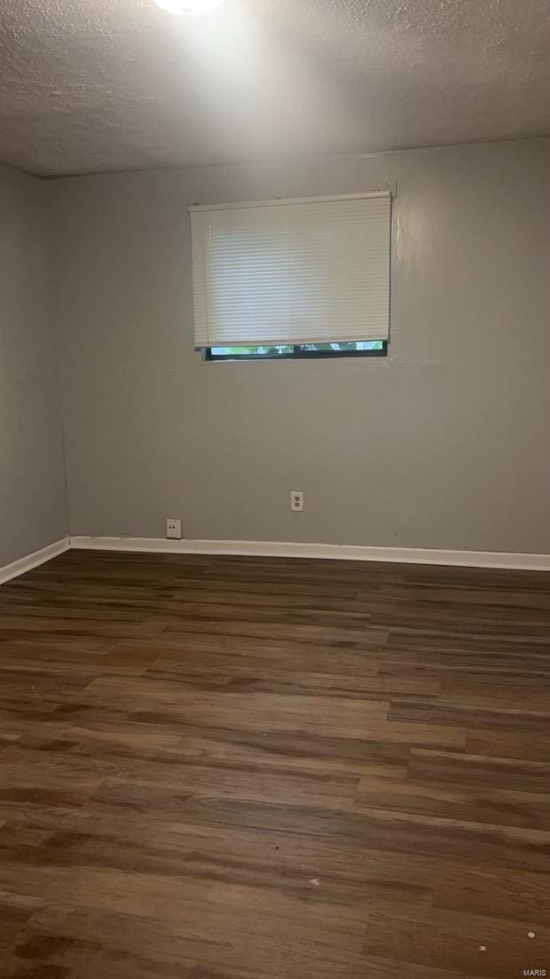 empty room with a textured ceiling and dark hardwood / wood-style floors