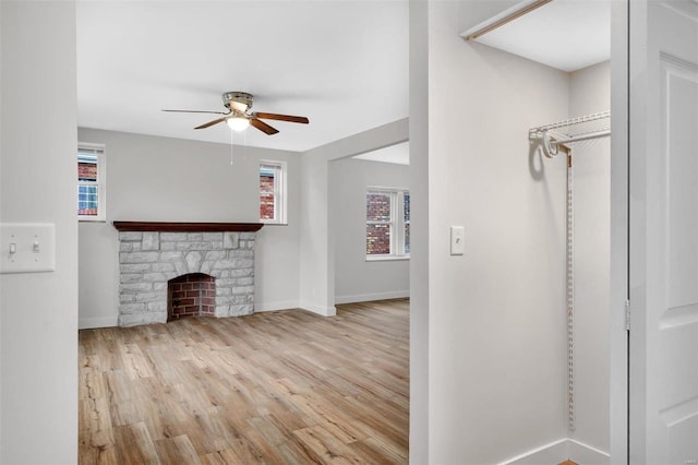 unfurnished living room featuring ceiling fan, a fireplace, and light hardwood / wood-style flooring