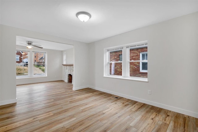 unfurnished living room featuring ceiling fan, light hardwood / wood-style floors, and a fireplace