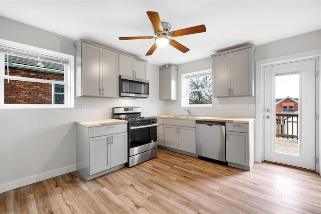 kitchen with gray cabinets, light hardwood / wood-style flooring, and appliances with stainless steel finishes