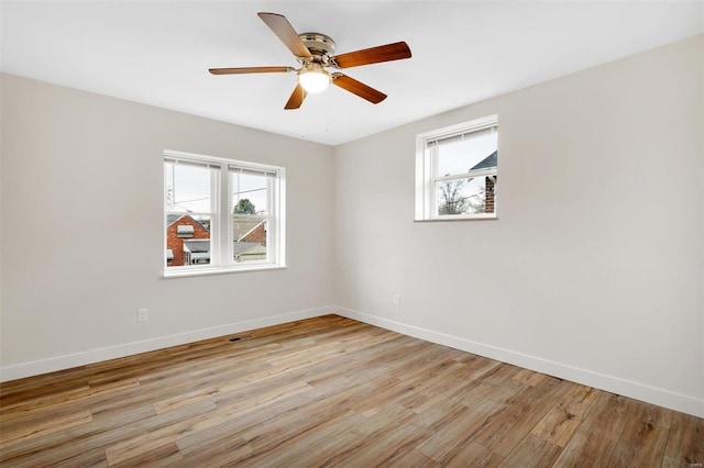 empty room with plenty of natural light, light hardwood / wood-style floors, and ceiling fan