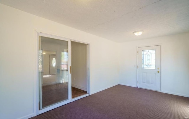 interior space with dark colored carpet and a textured ceiling