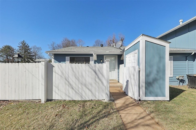 view of front facade featuring a storage shed, a front yard, fence, and an outbuilding