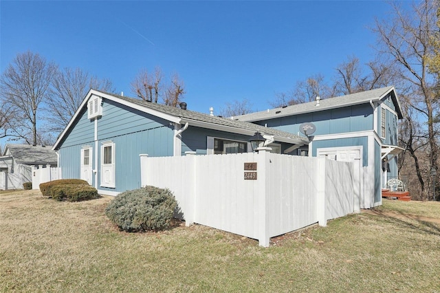 view of side of home featuring fence and a yard