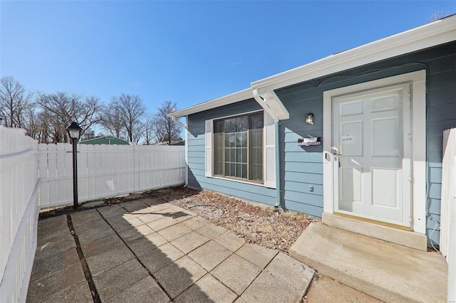 view of exterior entry featuring fence and a patio