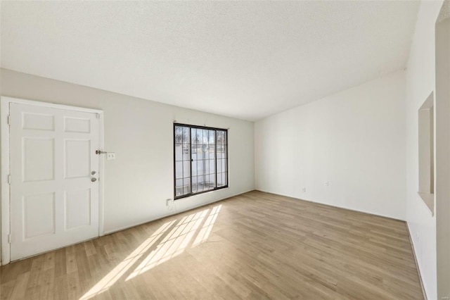 unfurnished room with a textured ceiling and light wood-type flooring