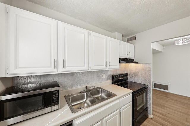 kitchen with black electric range oven, stainless steel microwave, visible vents, a sink, and ventilation hood